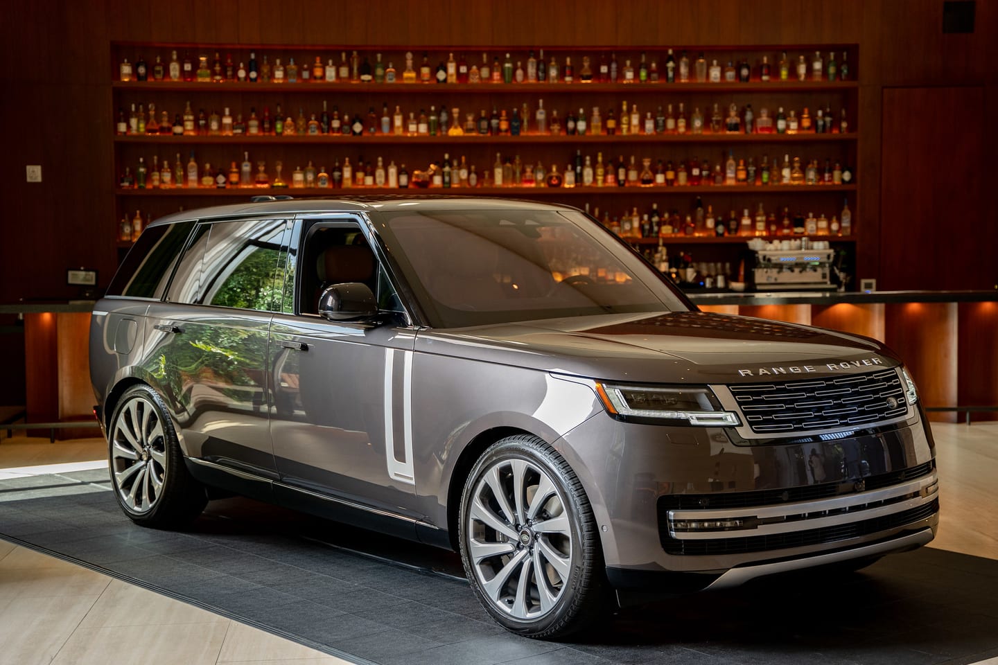 The new Range Rover staged in front of a backlit spirits bar at a launch event