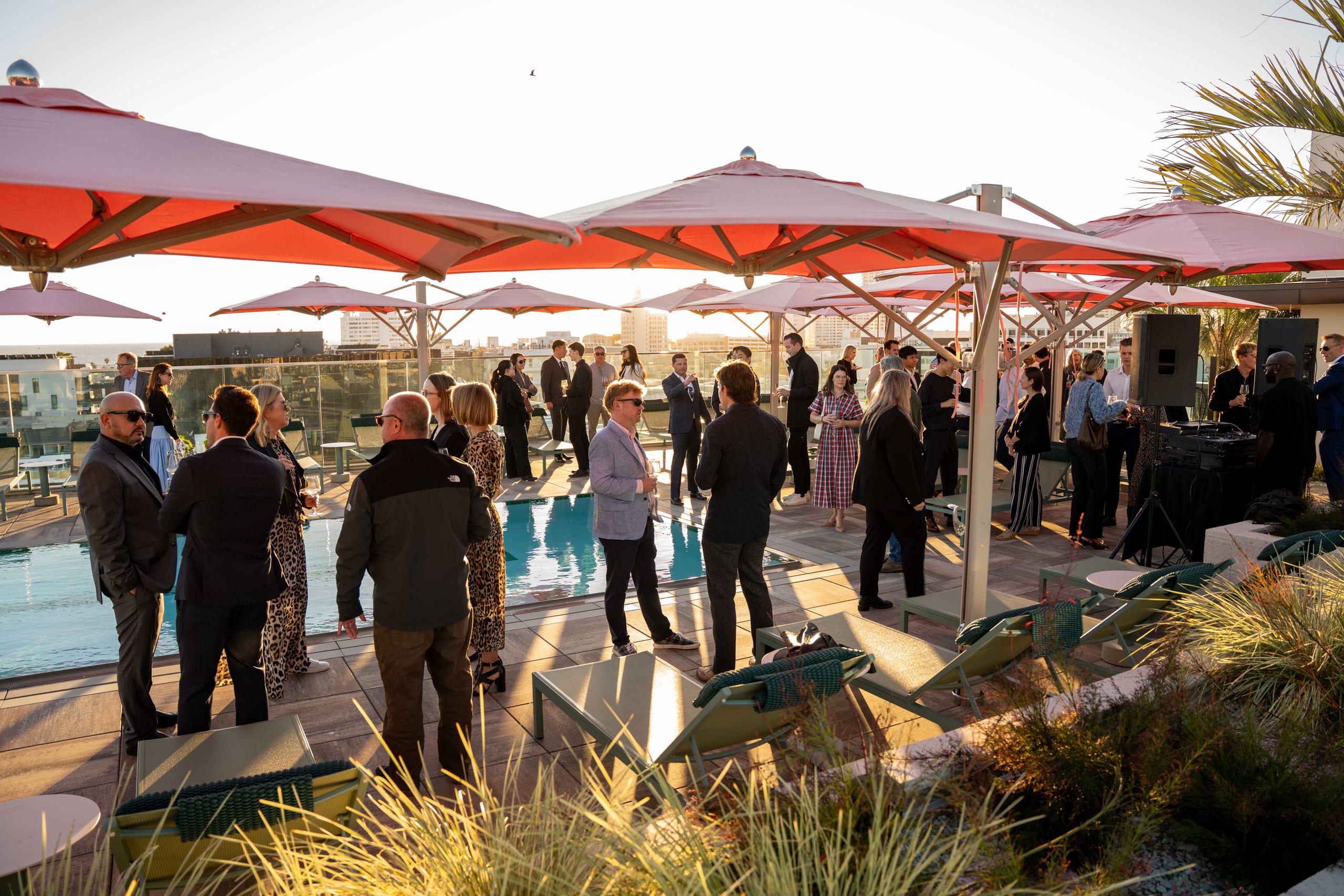Guests at a rooftop reception with umbrellas and a screen at 700 Broadway in Santa Monica