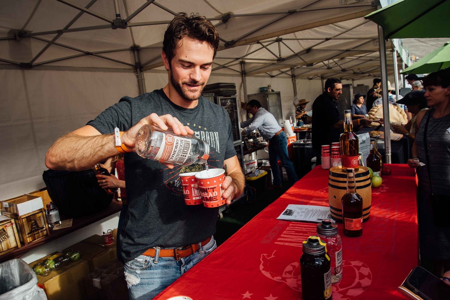 A vendor pouring a spirits tasting into cups at a tented bar at the Rose Bowl food and drink festival in Pasadena