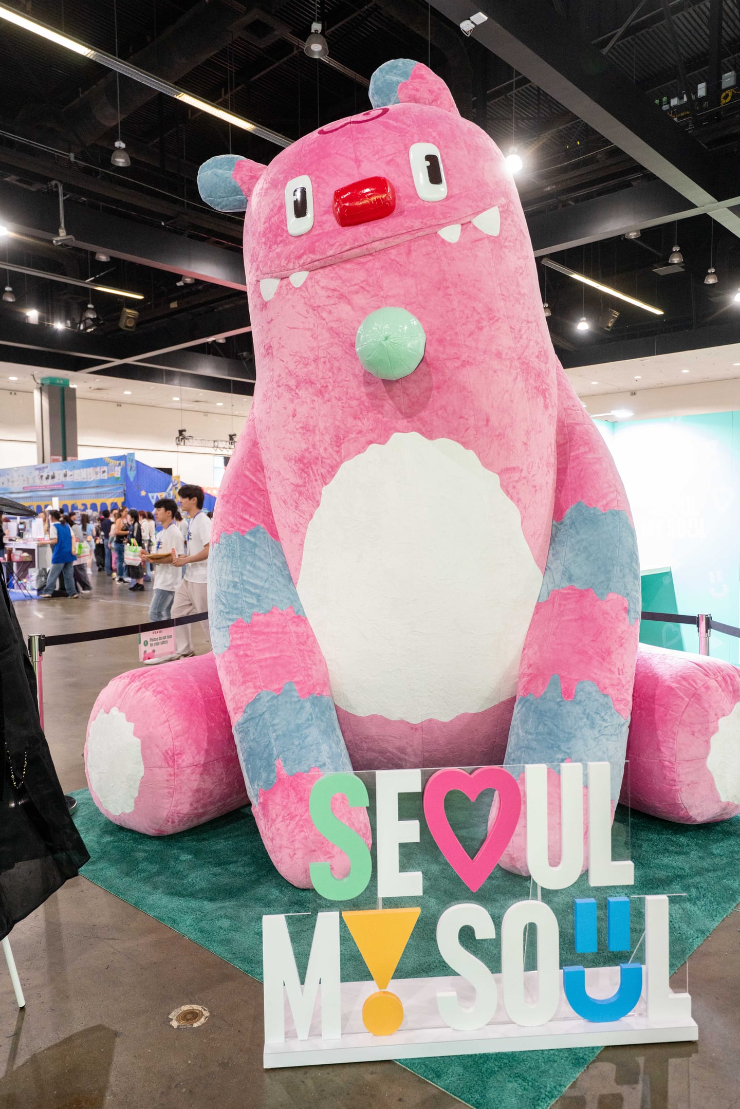 A giant pink plush mascot seated behind a Seoul My Soul sign at the Seoul tourism stand at KCON LA 2025