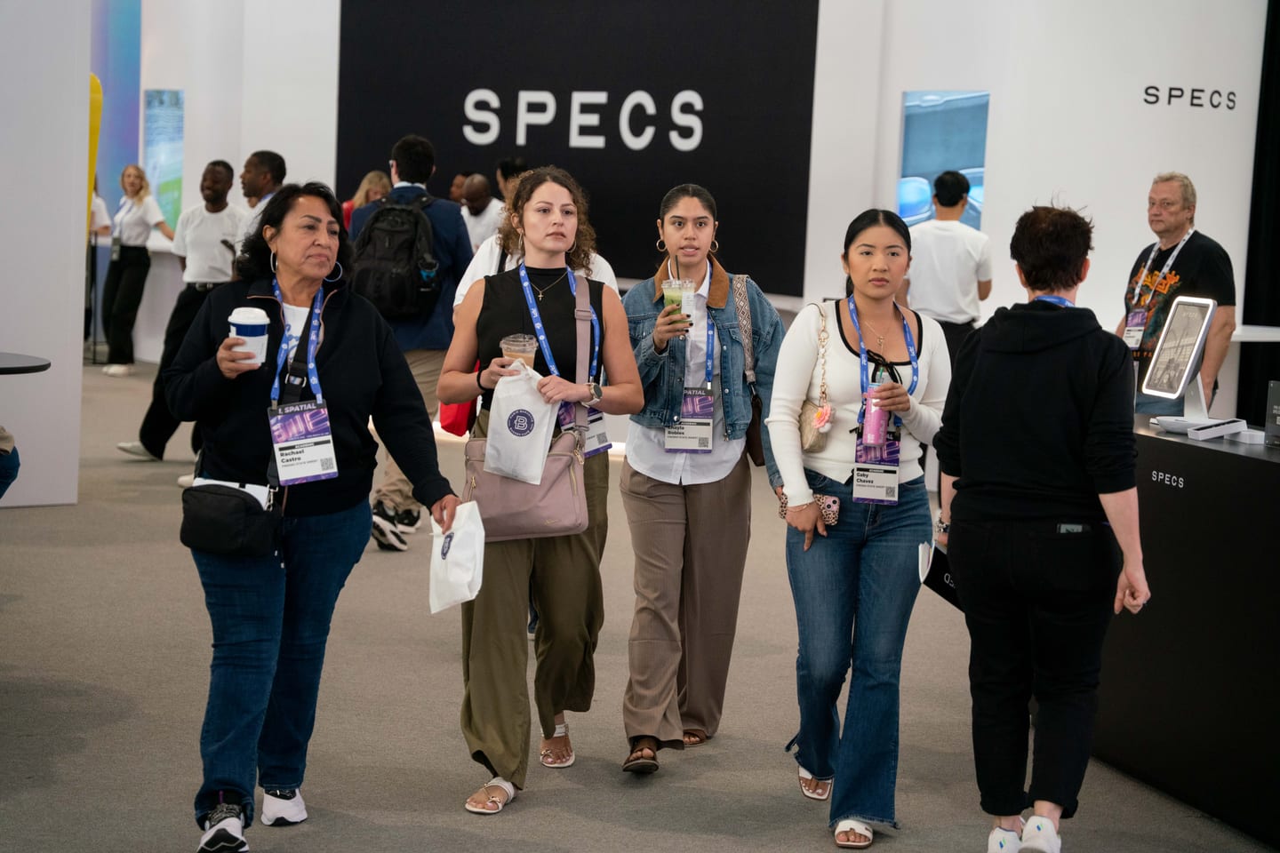 Attendees wearing lanyards walking through Snap’s white SPECS booth area at Augmented World Expo 2026