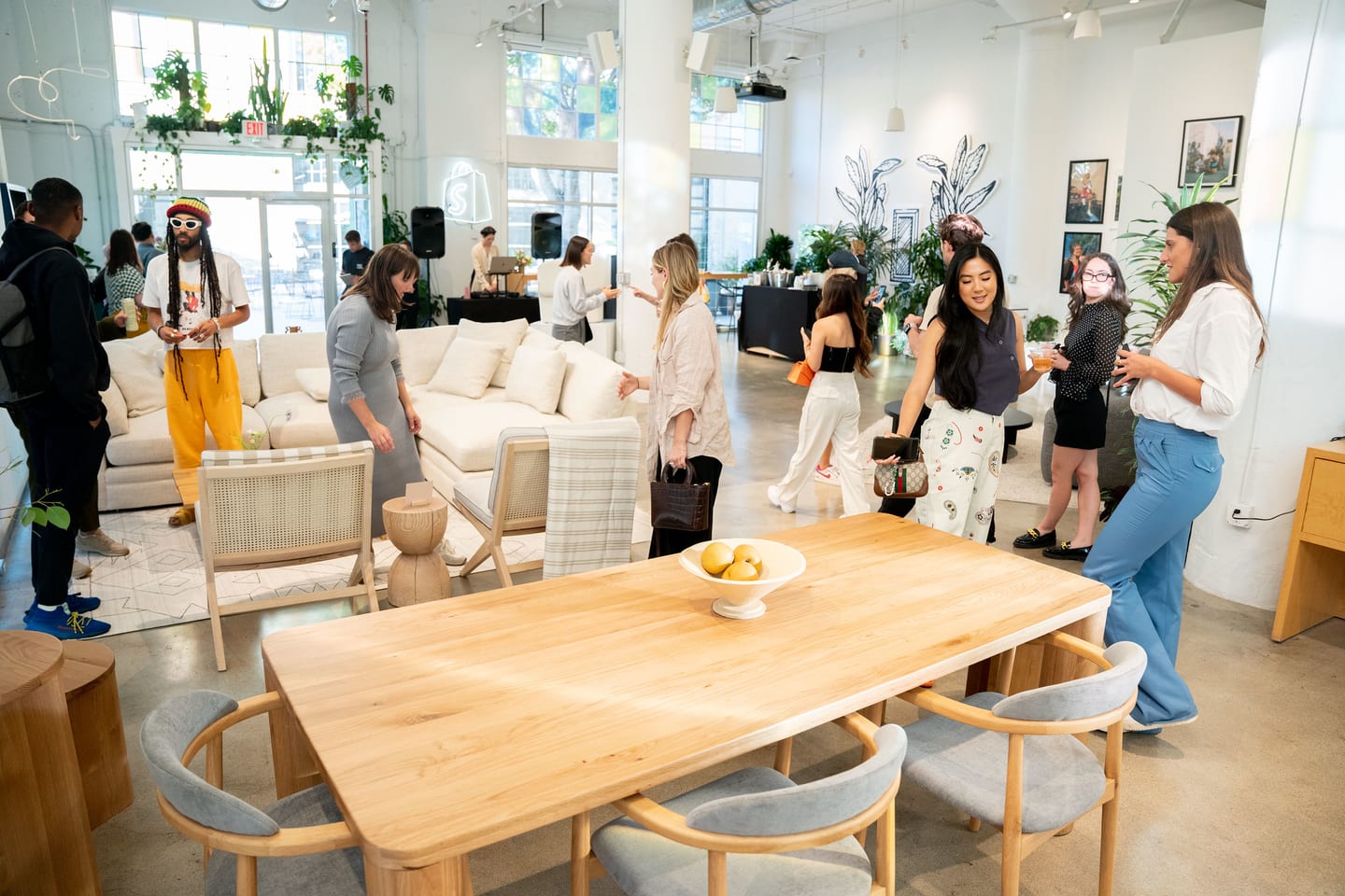 Guests mingling in a bright plant-filled loft at the Sundays nail-care brand pop-up