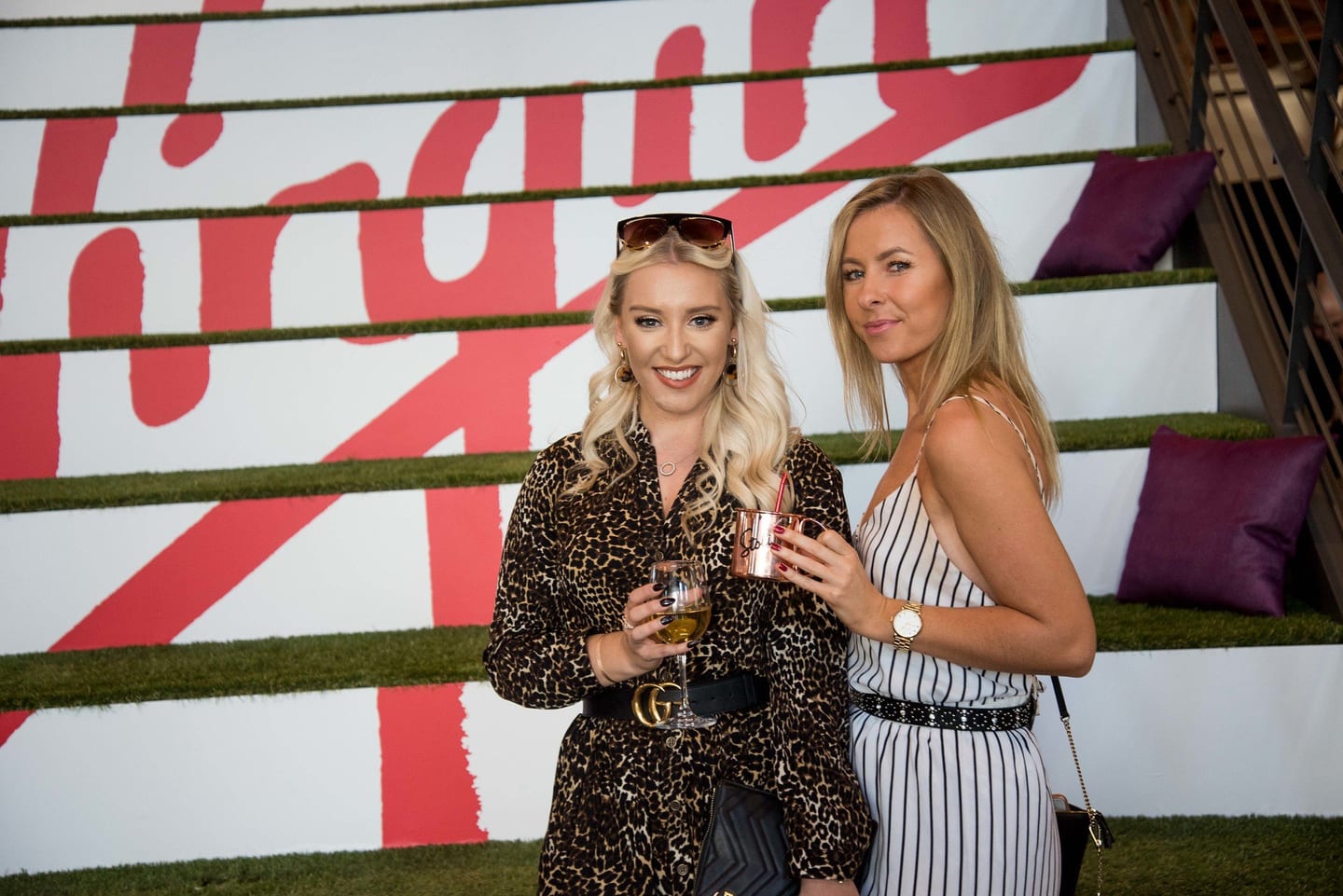 Two guests in front of a Virgin backdrop at a brand event