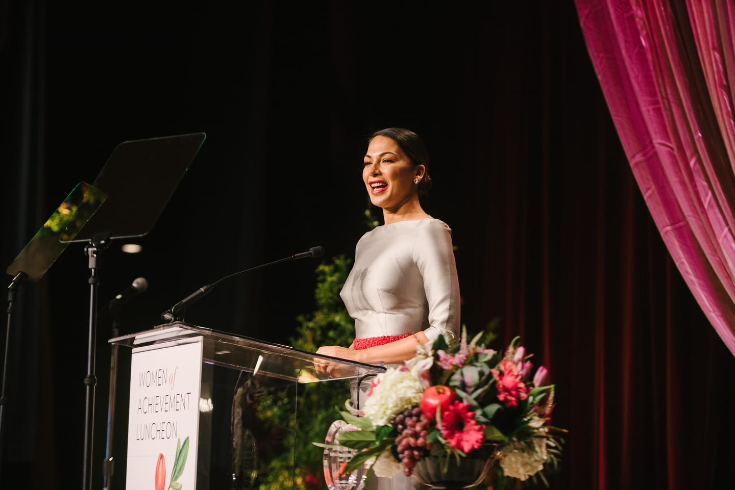 Speaker at a flower-dressed podium at the Women of Achievement luncheon